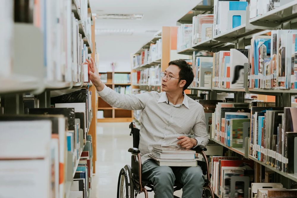 student in wheelchair in a library